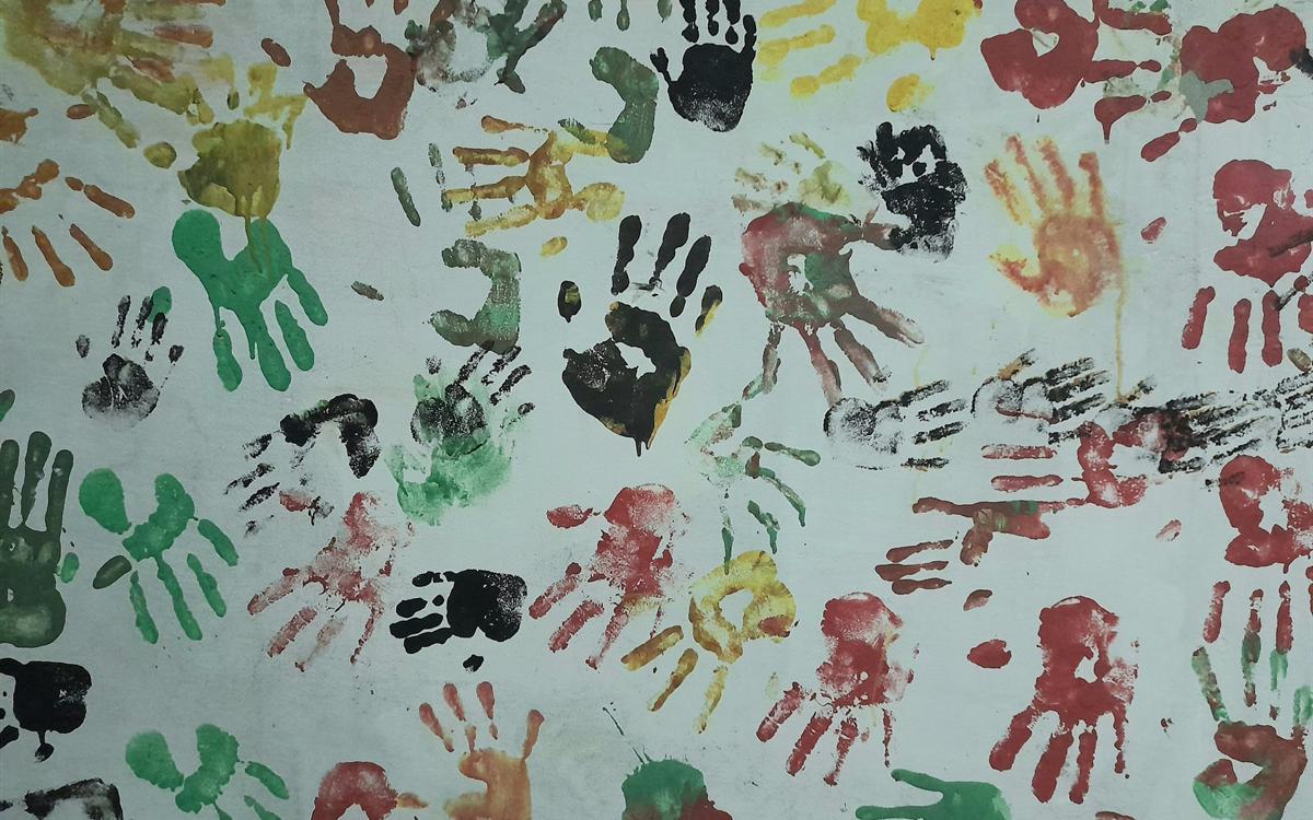 Muro cubierto de huellas de manos pintadas de colores